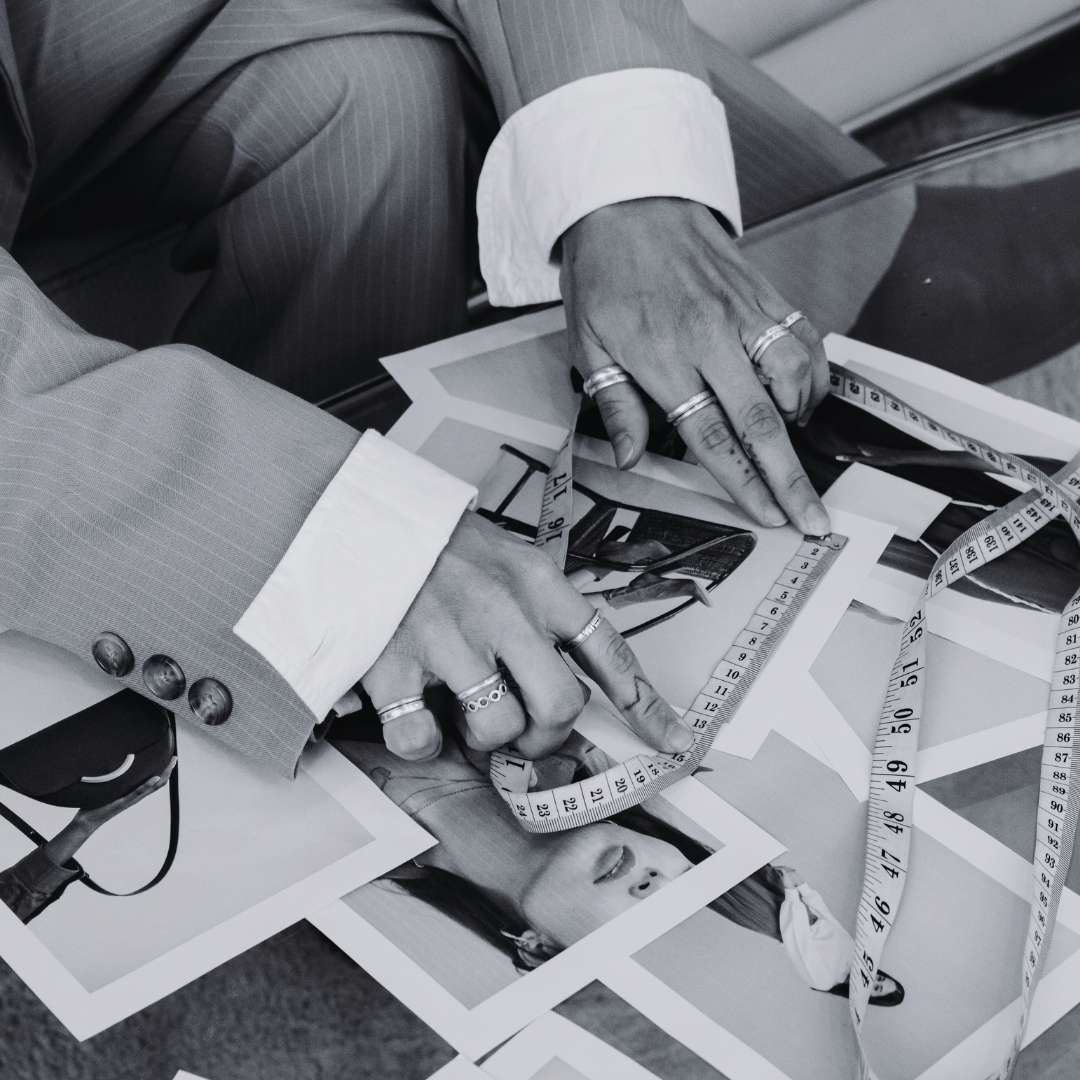 Hands arranging fashion sketches, fabric swatches and measuring tapes, branding and creative direction services