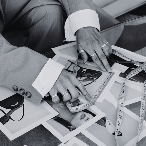 Hands arranging fashion sketches, fabric swatches and measuring tapes, branding and creative direction services