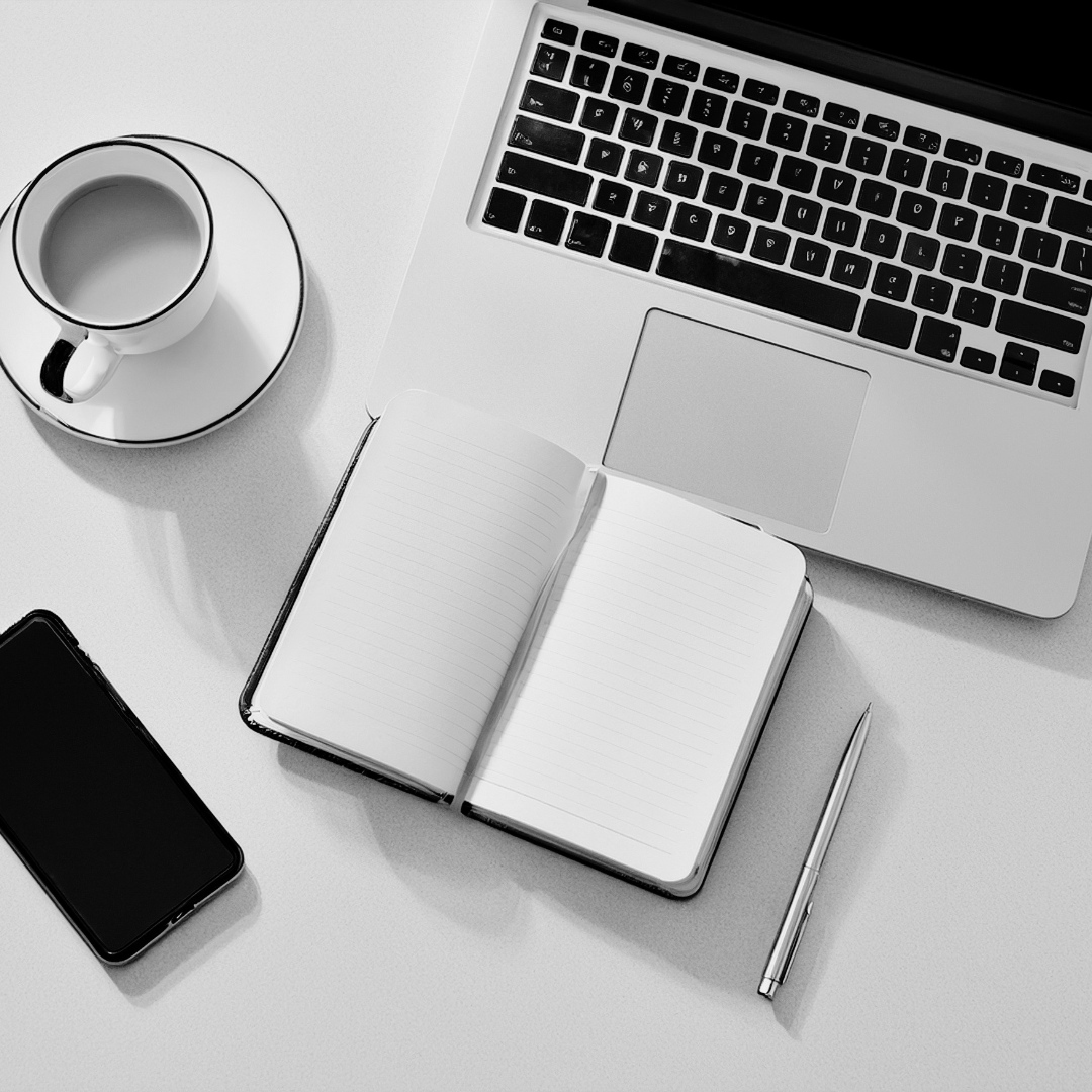 Desk with a laptop, coffee cup, smartphone and open notebook, outsourced customer service for small businesses